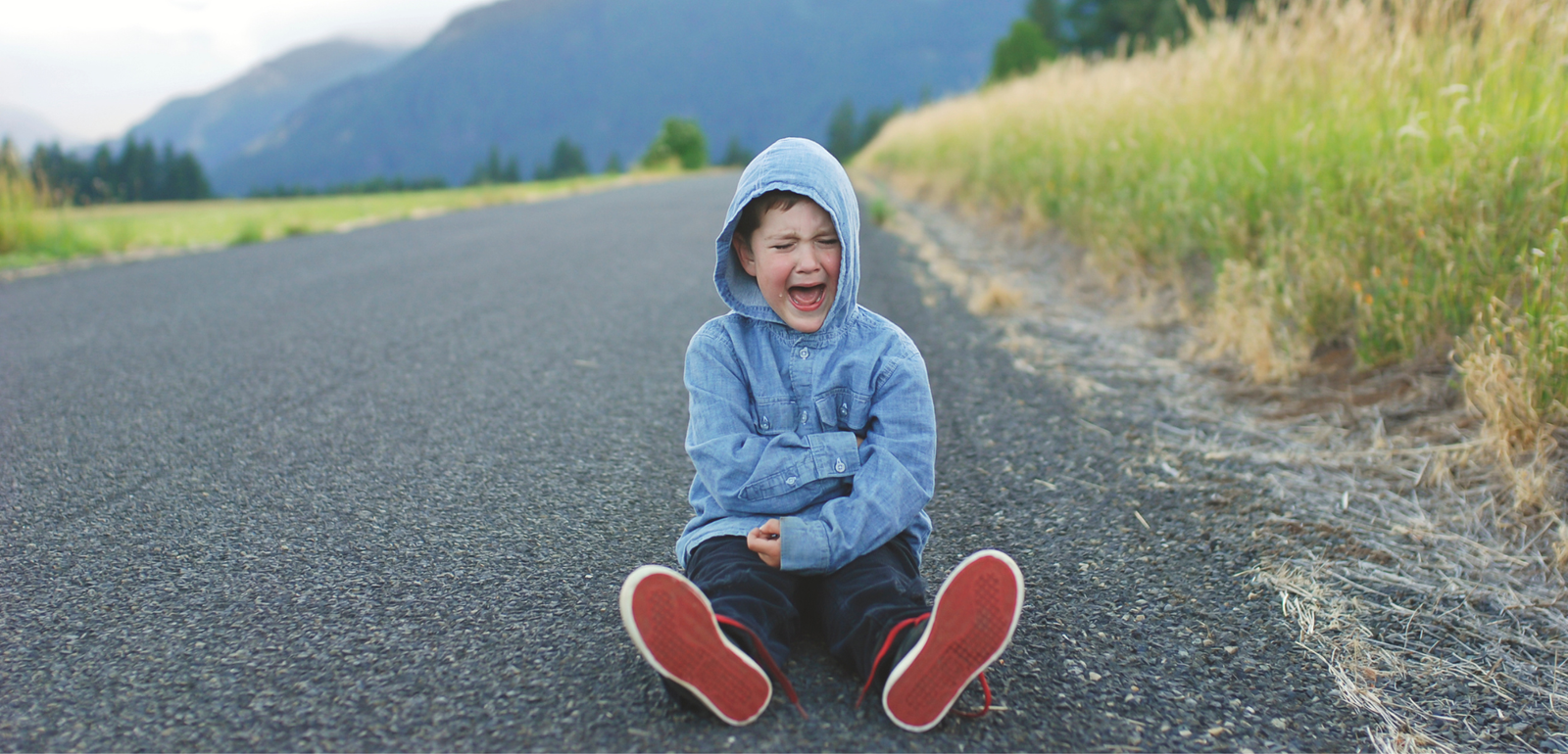 boy sitting on road crying and having a tantrum